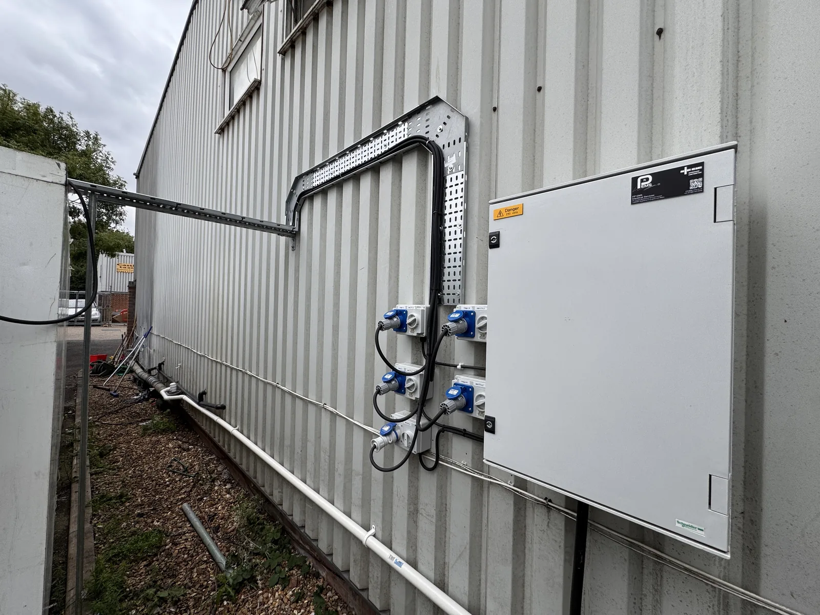 Exterior electrical distribution cabinet, sockets and cable tray on an industrial building.