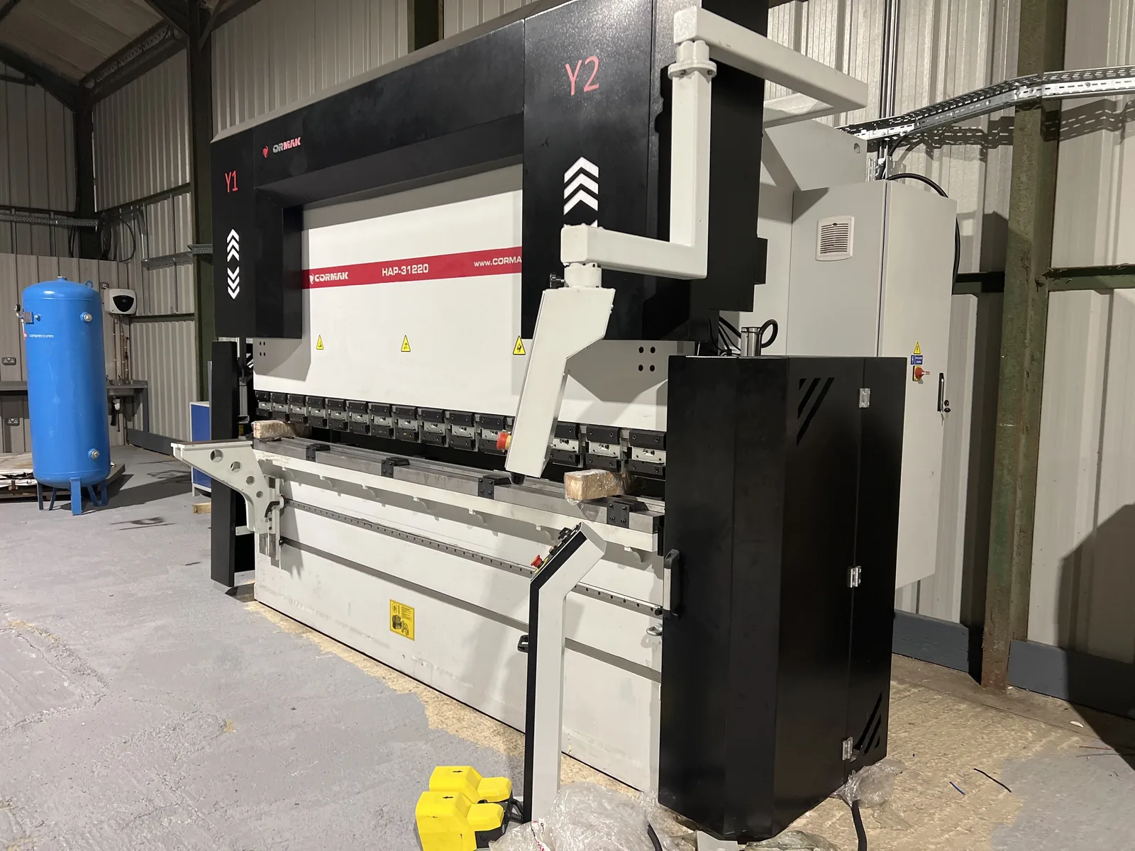Press brake machinery and overhead cable containment in a manufacturing workshop.