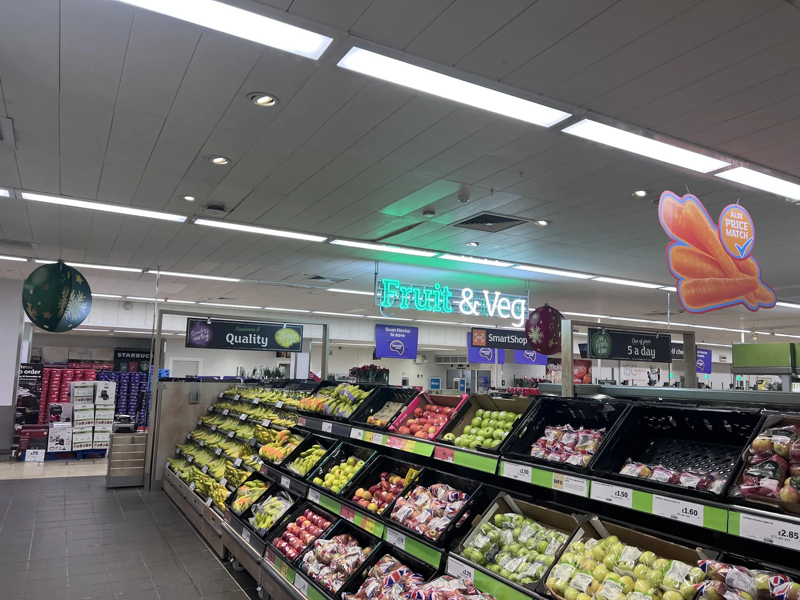 Linear and recessed ceiling lighting above supermarket produce aisles.